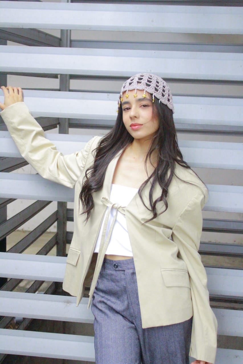 Pose editorial con blazer claro frente a persiana